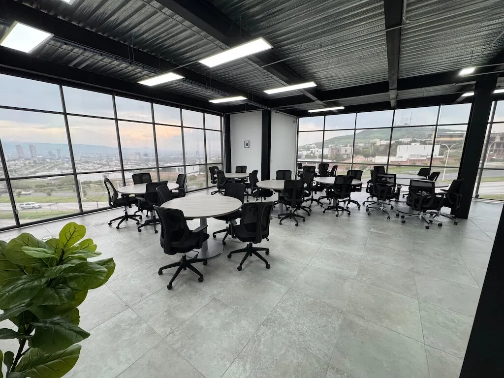 Espacio colaborativo con escritorios y ventanales hacia los cerros de León