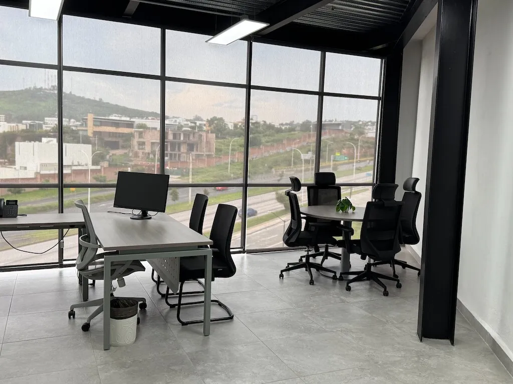 Oficina con escritorio y mesa de reuniones frente a ventanales