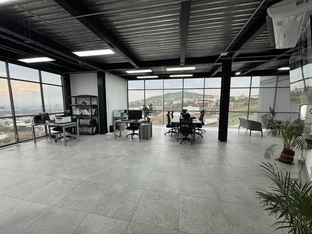 Piso de oficinas abierto con estaciones de trabajo y ventanales